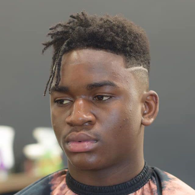 A young man is getting his hair cut at a barber shop.