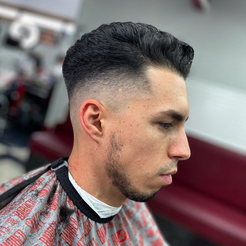 A man is getting his hair cut at a barber shop.