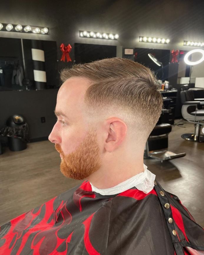 A man with a beard is getting his hair cut at a barber shop.