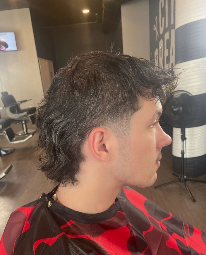 A man is getting his hair cut at a barber shop.