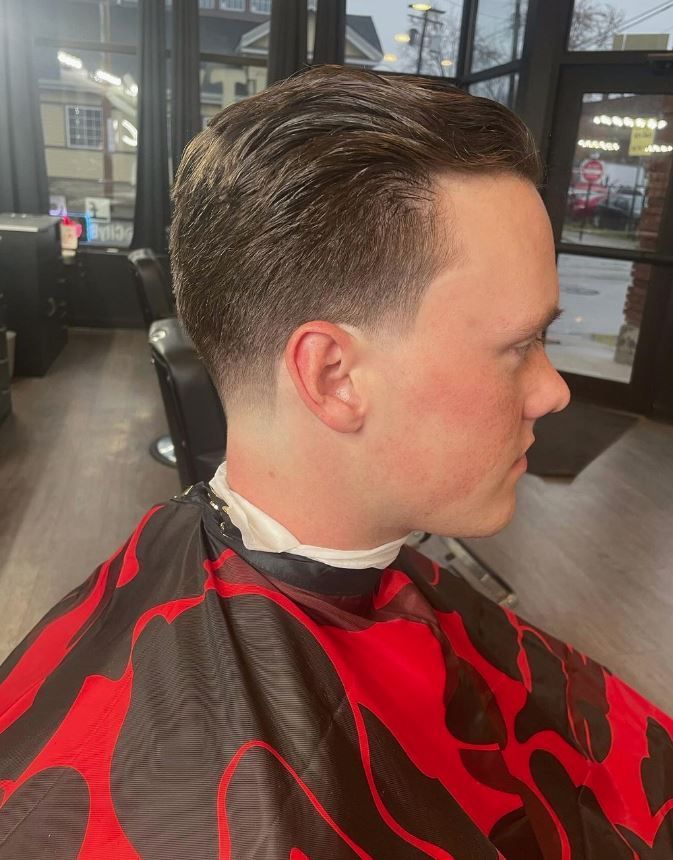 A man is getting his hair cut at a barber shop.