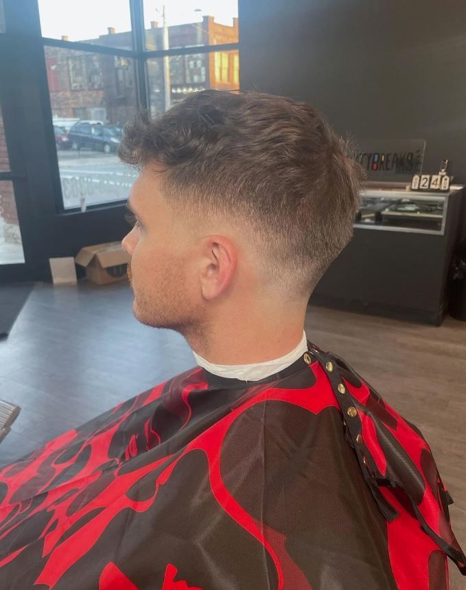 A man is getting his hair cut at a barber shop.