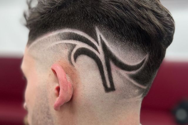 The back of a man 's head with a tattoo on it.