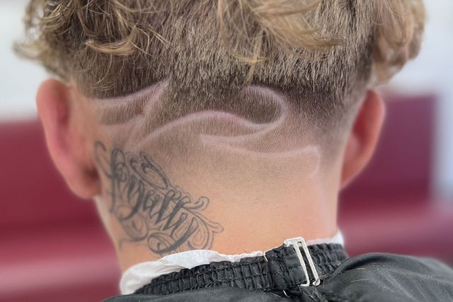 The back of a man 's head with a tattoo on his neck.