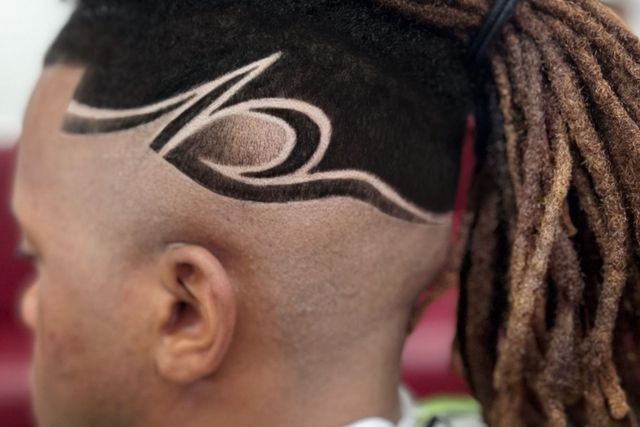 A man with dreadlocks has a tattoo on his head