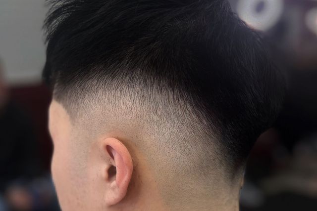 A close up of a man 's head with a fade haircut.