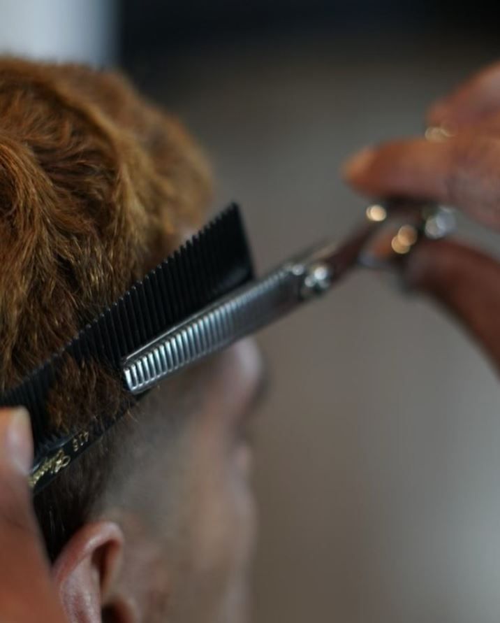 A person is getting their hair cut with scissors and a comb.