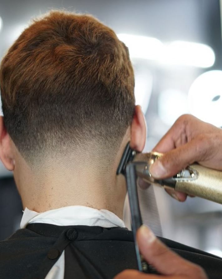 A man is getting his hair cut by a barber