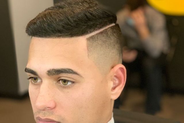 A man is getting his hair cut at a barber shop.