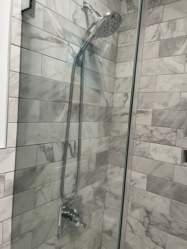 Chrome showerhead and handheld shower in a tiled bathroom shower stall
