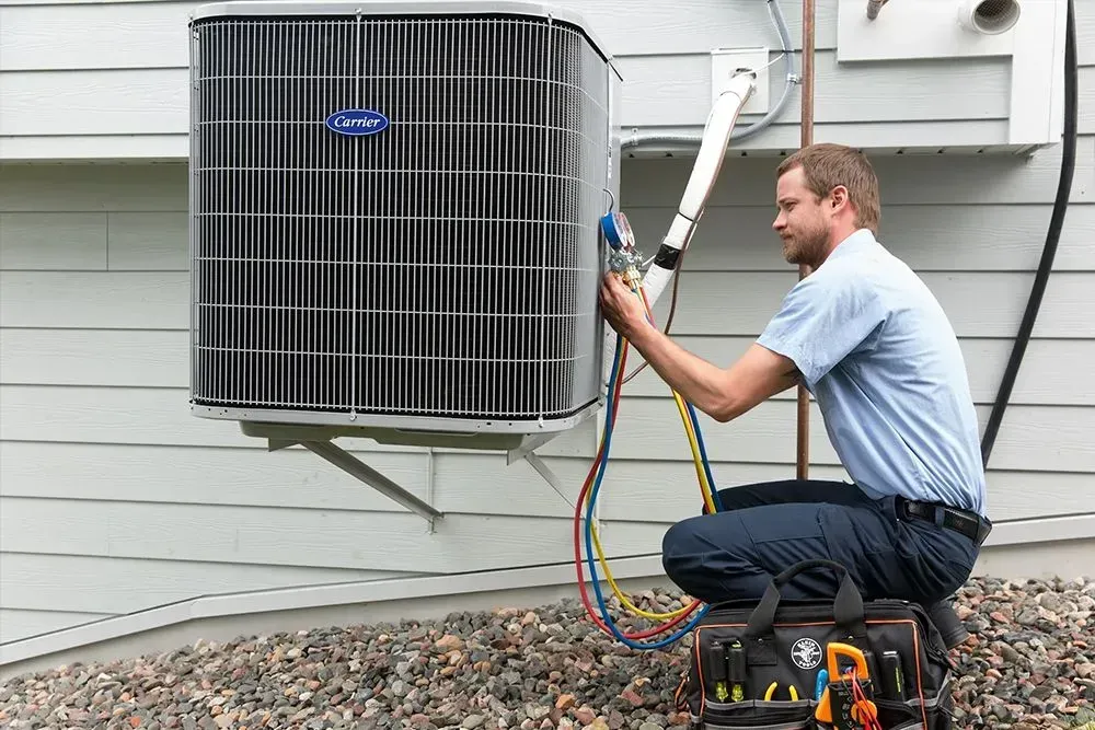 HVAC technician servicing an air conditioner unit outdoors, using gauges and tools.