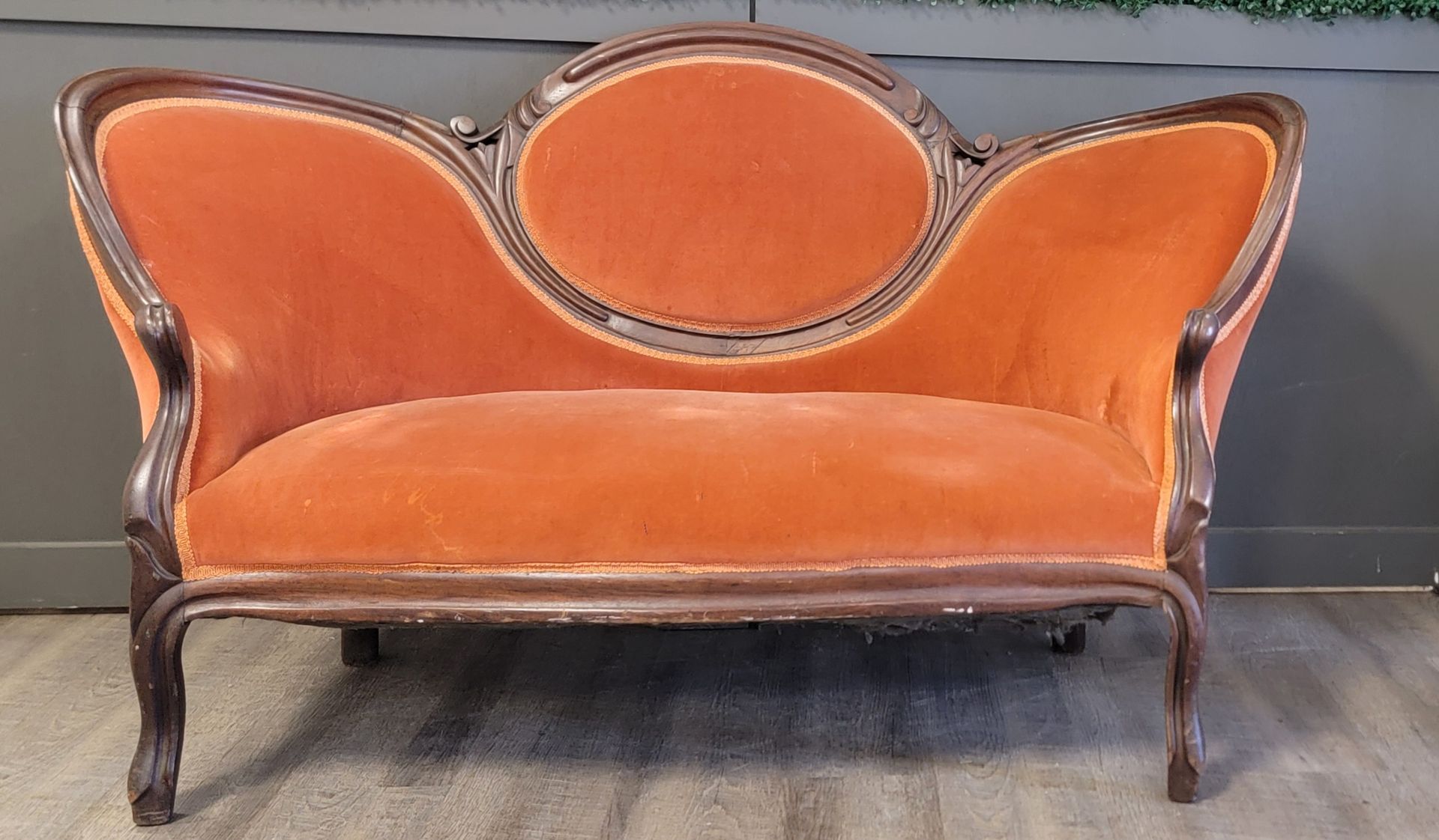 An orange couch is sitting on a wooden floor in front of a wall.