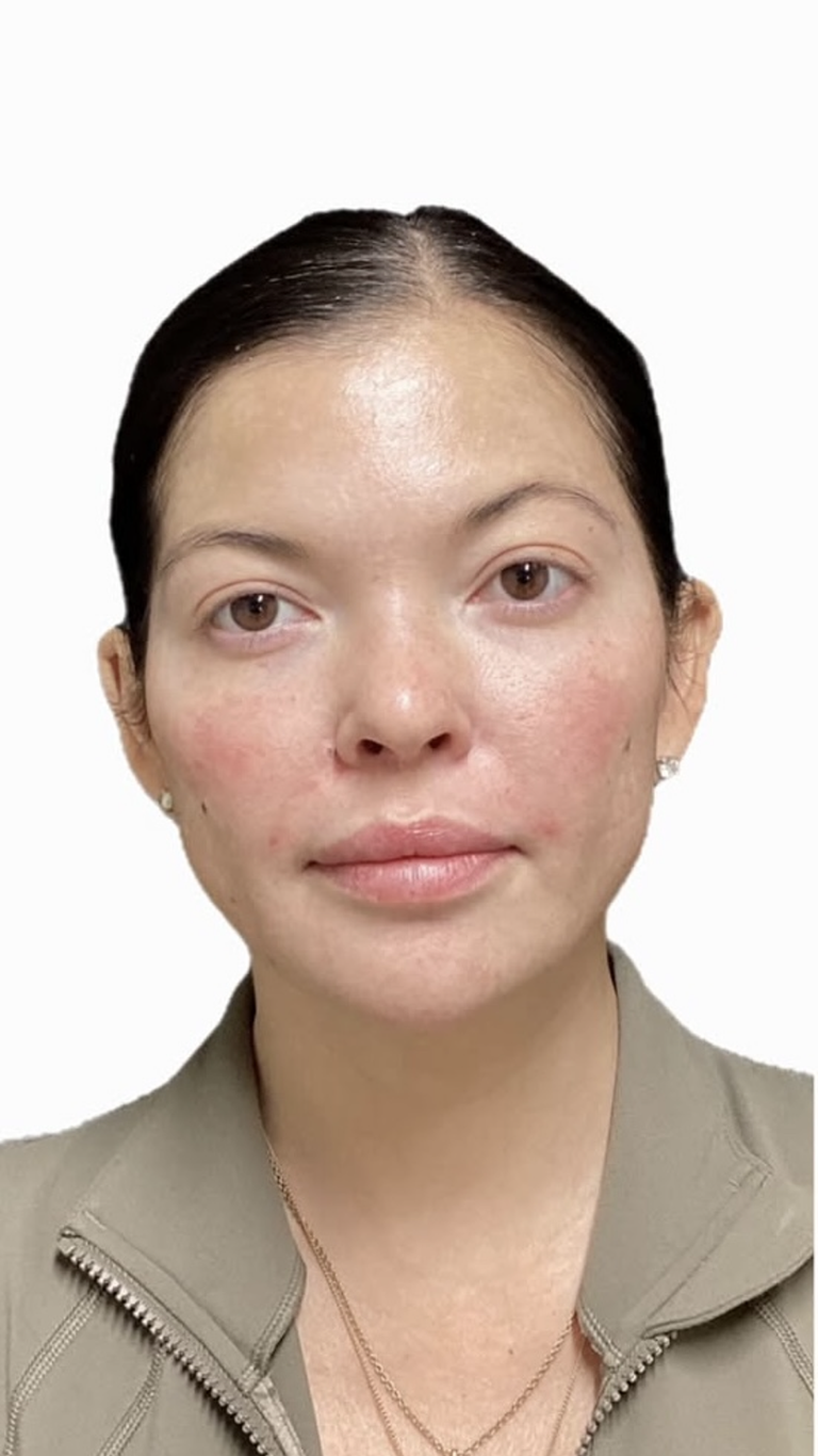 Woman with dark hair in a tan jacket, looking at the camera.