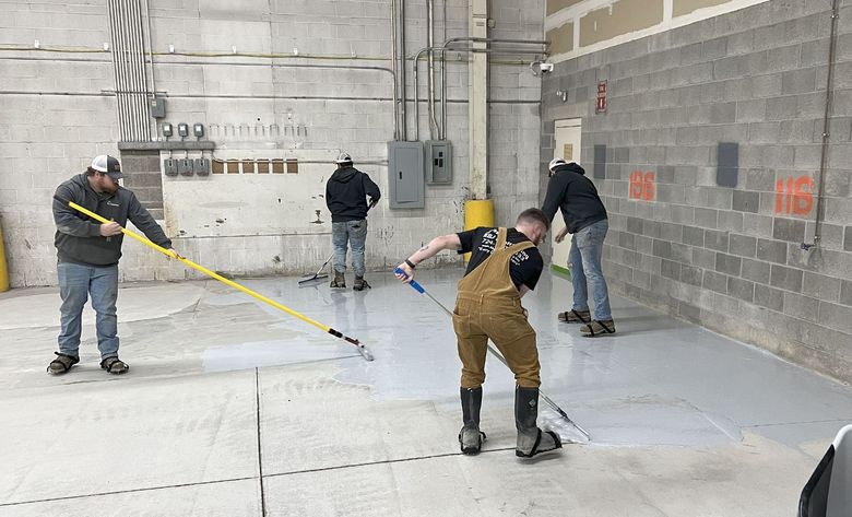 A group of men are cleaning the floor of a building.