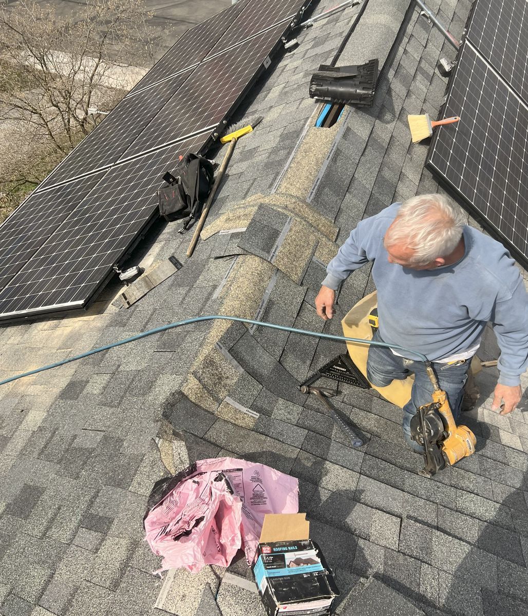 A man is working on a roof with solar panels.