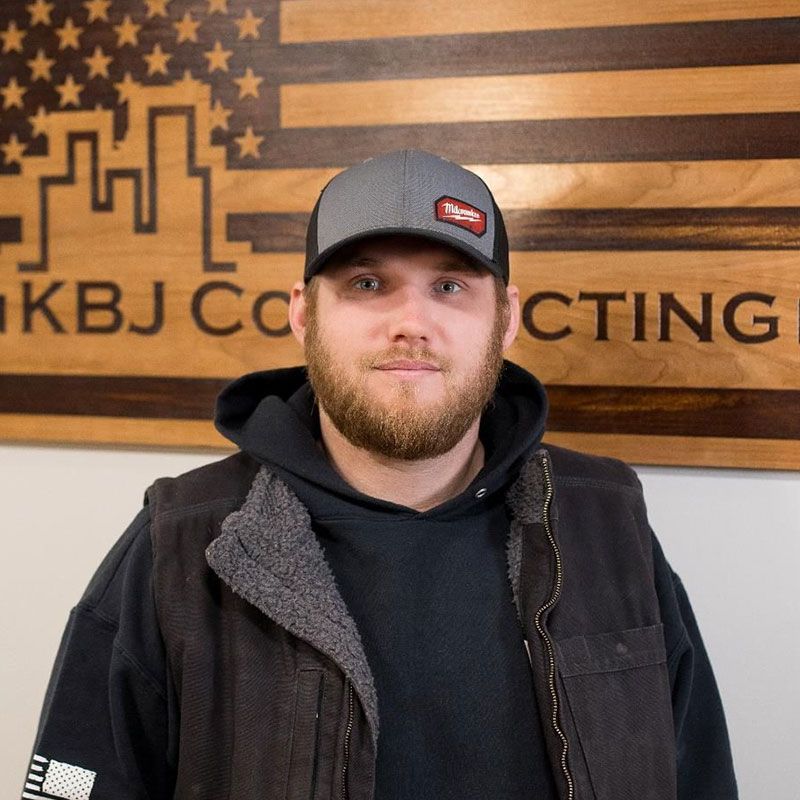 A man standing in front of a sign that says kbj contracting