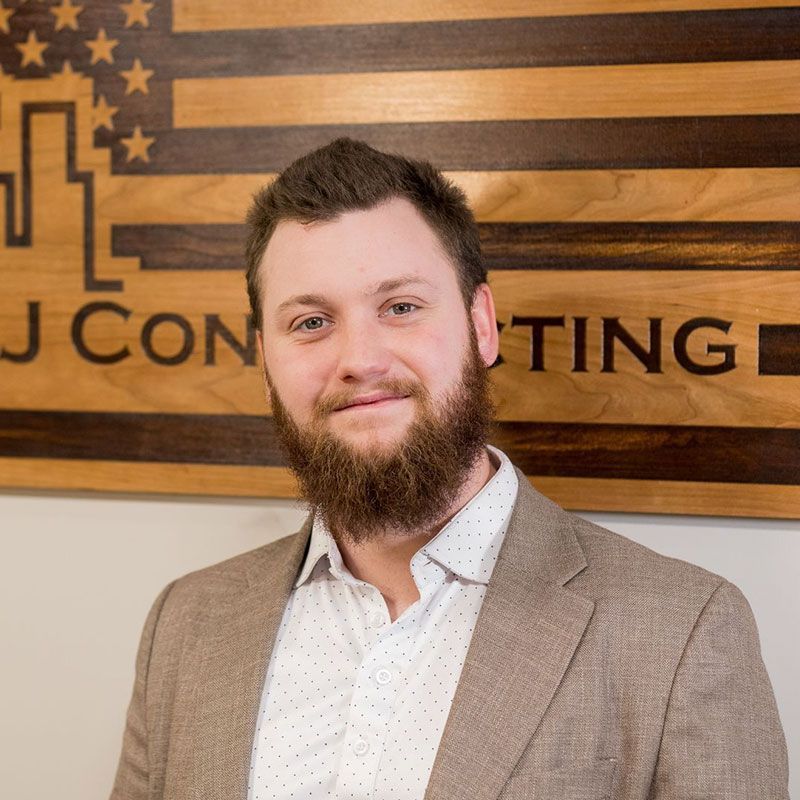 A man with a beard is standing in front of a wooden american flag.