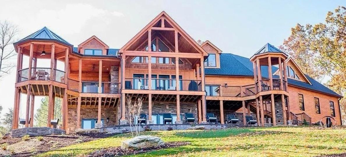 A large wooden house with multiple levels, decks, and two gazebo-like structures.