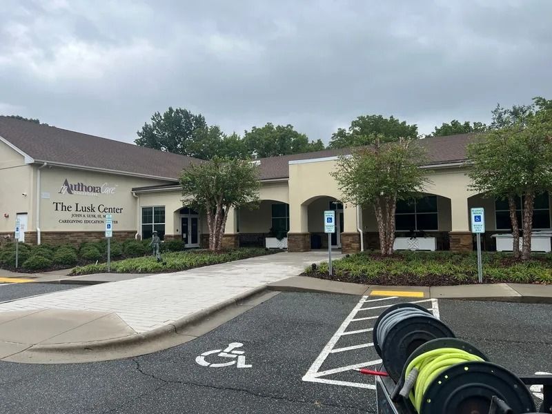 Exterior of The Link Center, a beige building with a wheelchair accessible entrance. Cloudy sky overhead.
