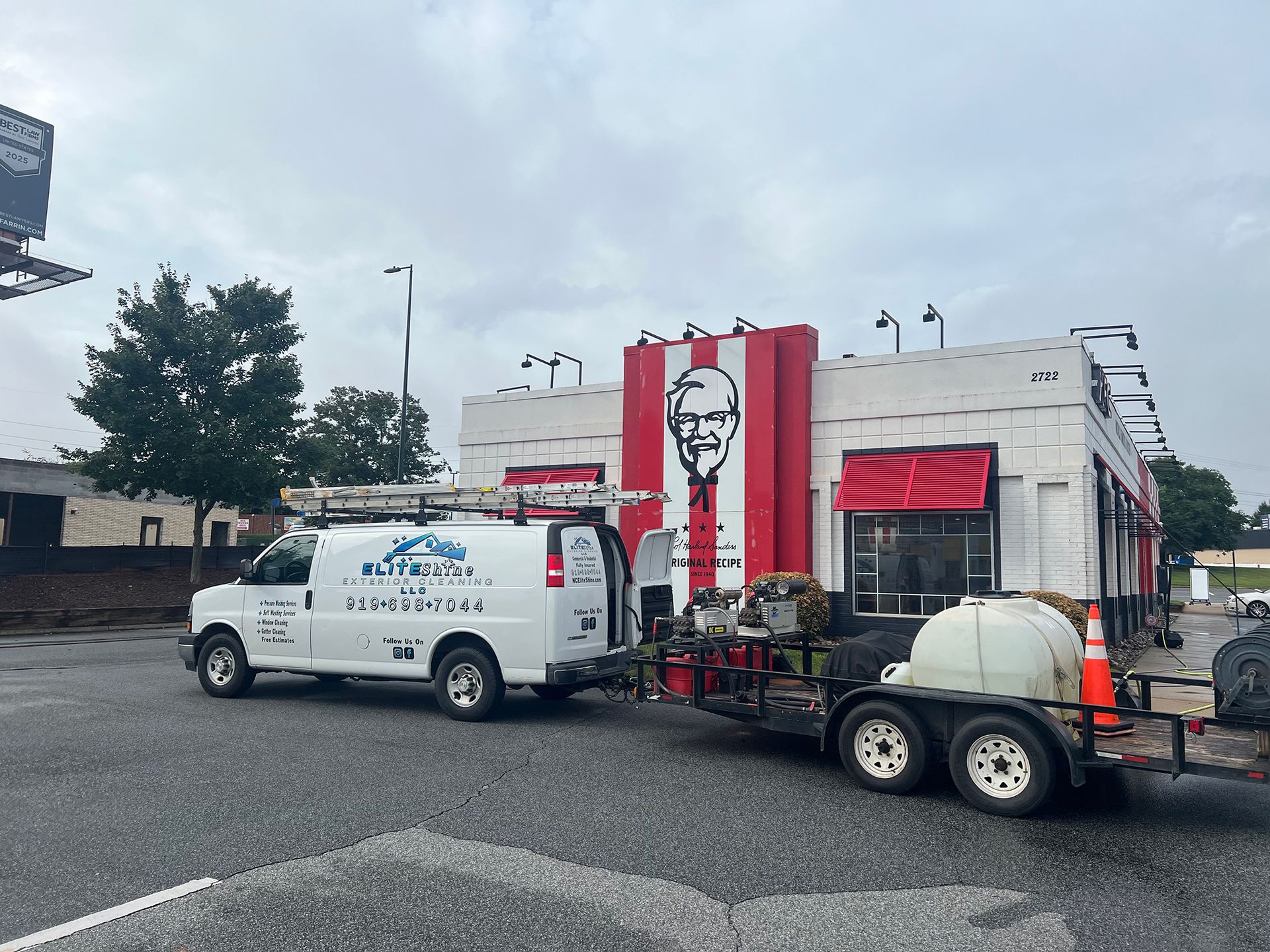 A white van and trailer parked in front of a KFC restaurant.