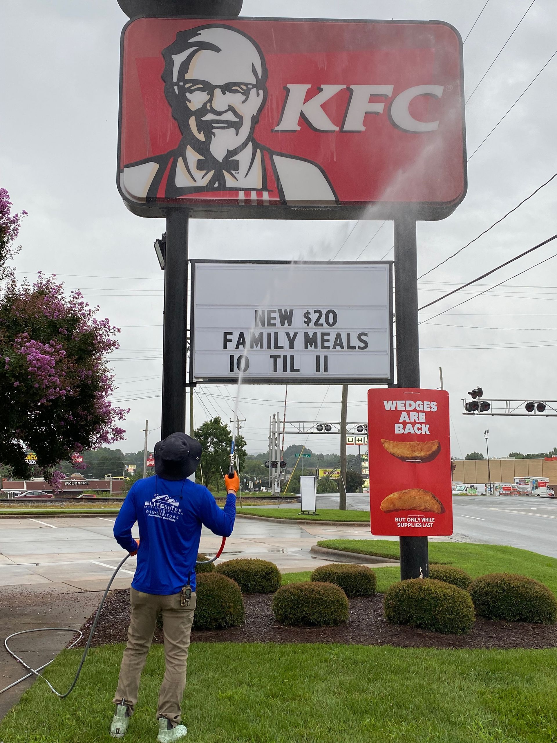 Person power washing a KFC sign. The sign displays 