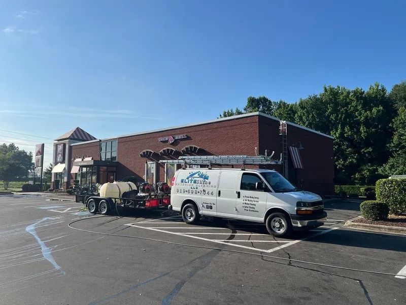 White van and trailer parked near a brick building, likely for power washing.