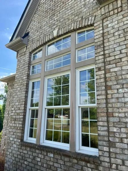 Brick home exterior with large windows; reflections of trees and sky.