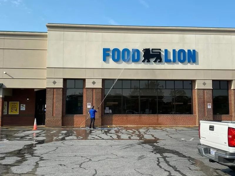 A person power washing the front of a Food Lion grocery store.