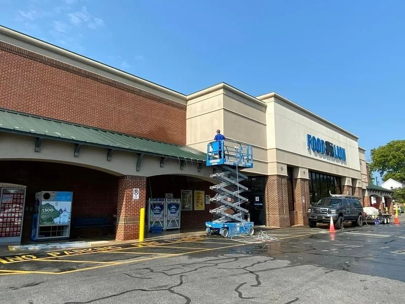 Exterior of Food Lion grocery store; person on a lift working on the building.