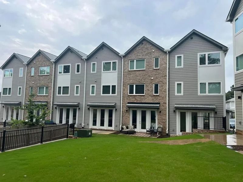 Row of modern townhouses with gray siding, brick accents, and green lawn.