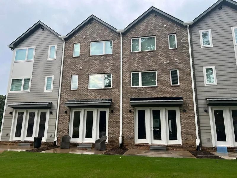 Row of townhouses with gray siding and brick facades; glass doors and windows.