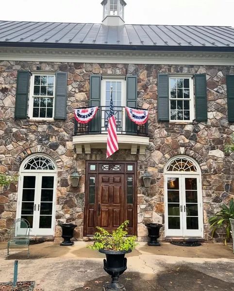 Stone house with American flag, red and blue bunting, and dark wood door.