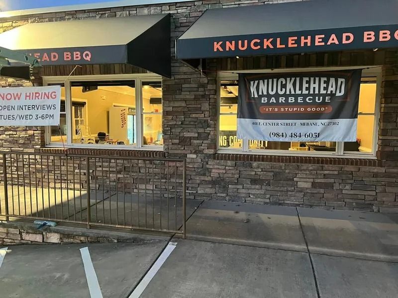 Knucklehead Barbecue restaurant with stone exterior. Now Hiring sign in window.