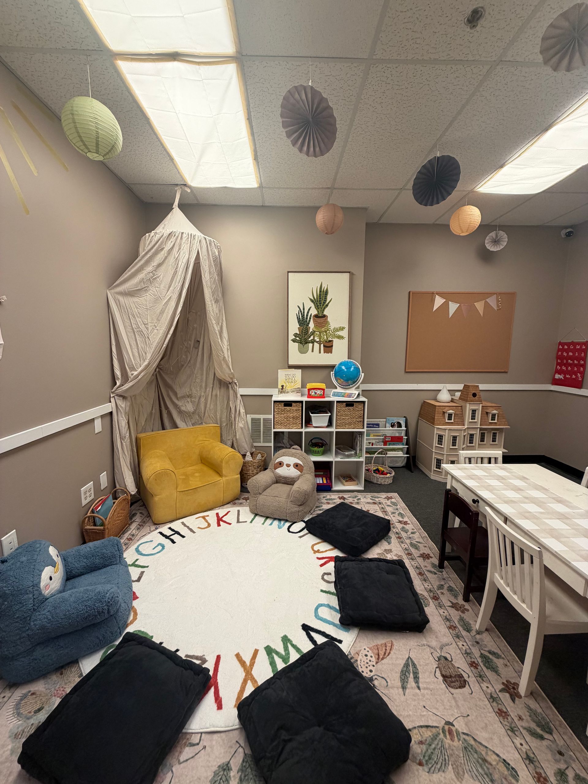 Cozy child’s playroom with tent, toys, cushions, bunting, and Christmas-themed rug under paper lanterns