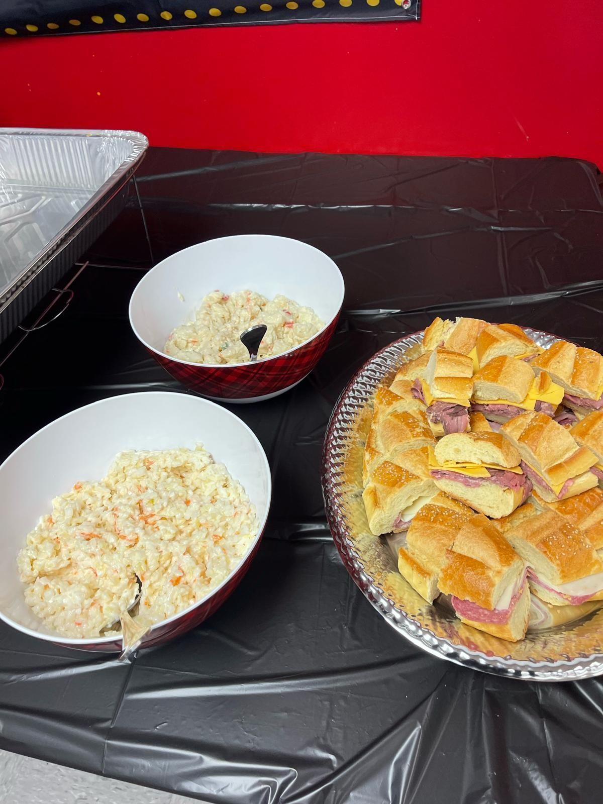 Three bowls and a tray of sliced bread on a black table with a red background.