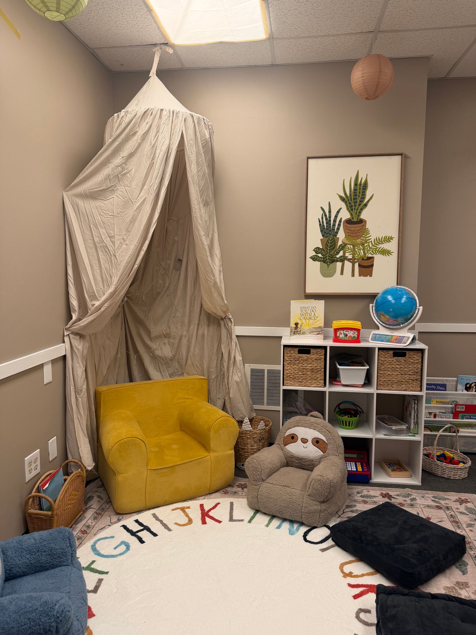Cozy playroom corner with a yellow chair, stuffed animals, storage cubbies, and wall art
