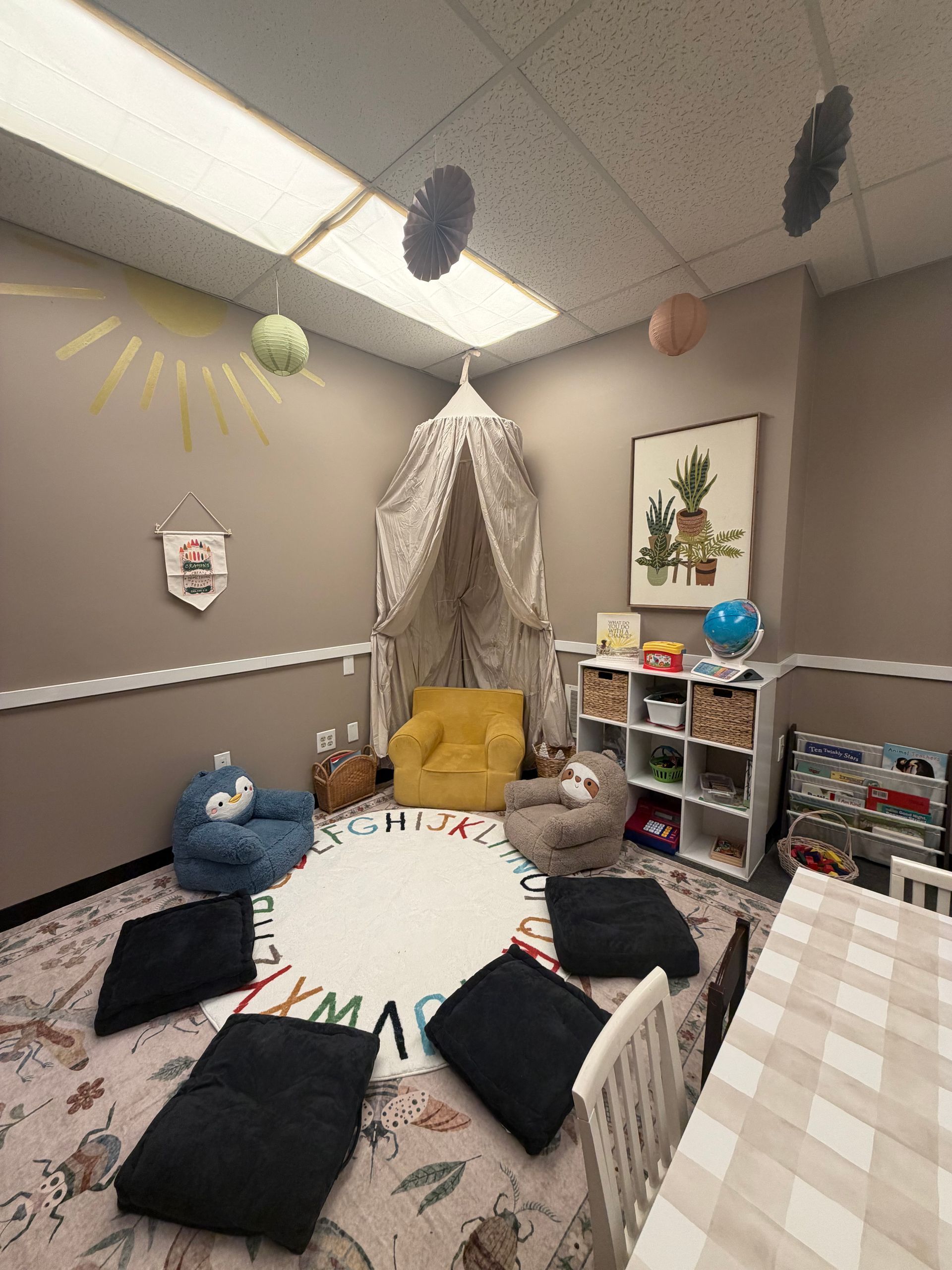 Cozy child’s playroom with bed, cushions, toys, hanging pom-poms, and soft neutral decor