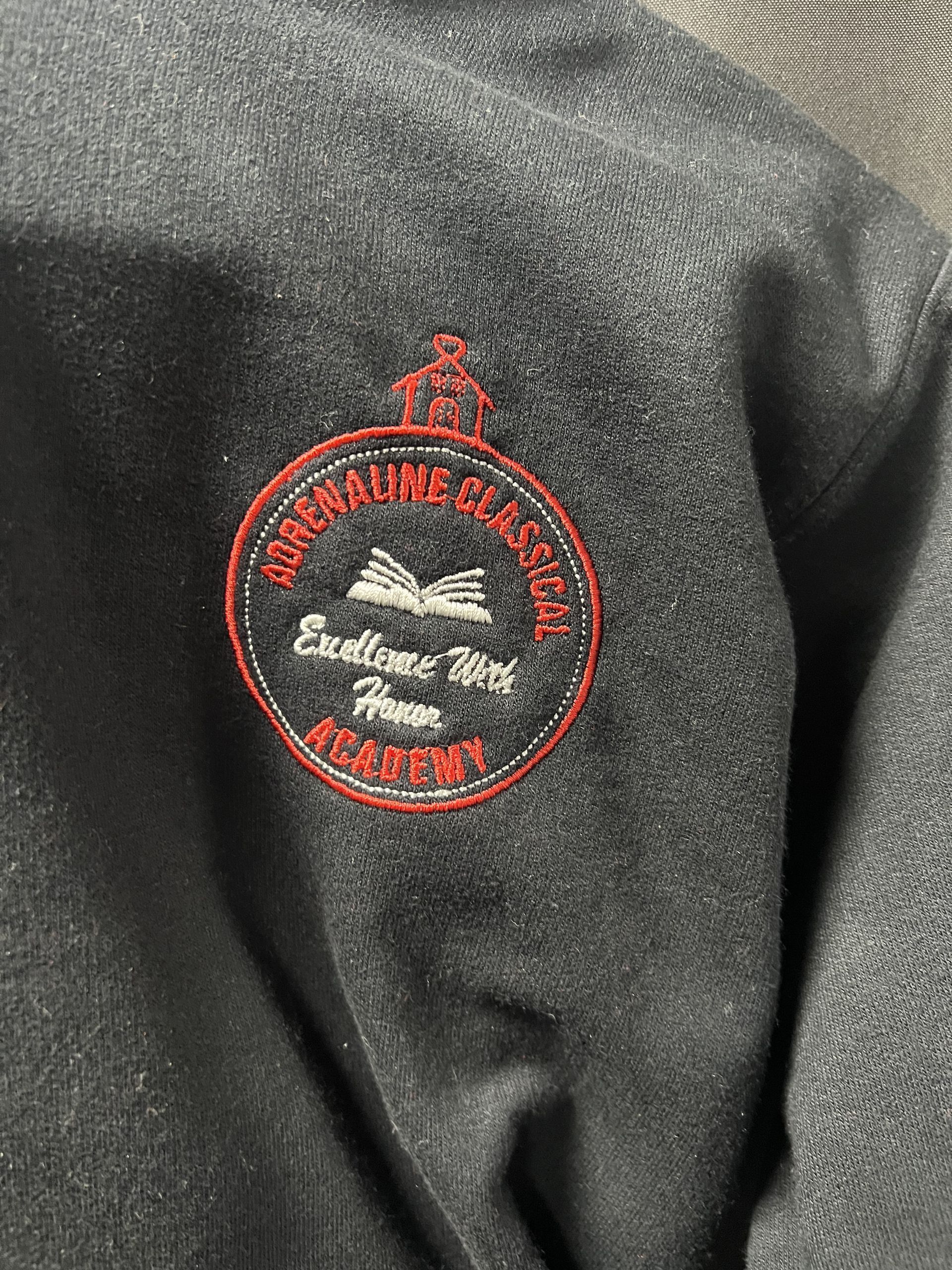 Close-up of black fabric with a red embroidered circular logo and white cursive text