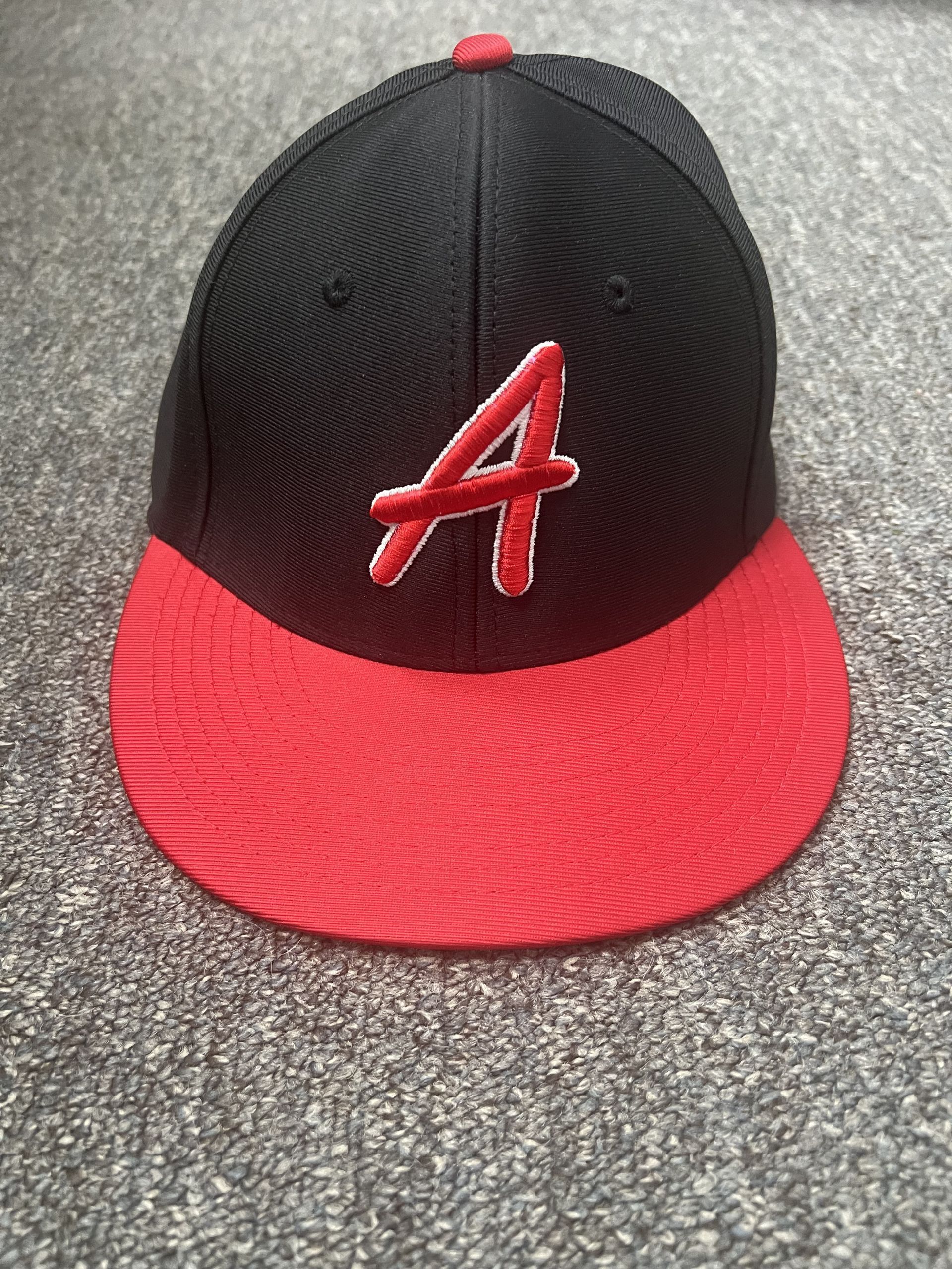 Black and red baseball cap with a red “A” logo on a gray surface