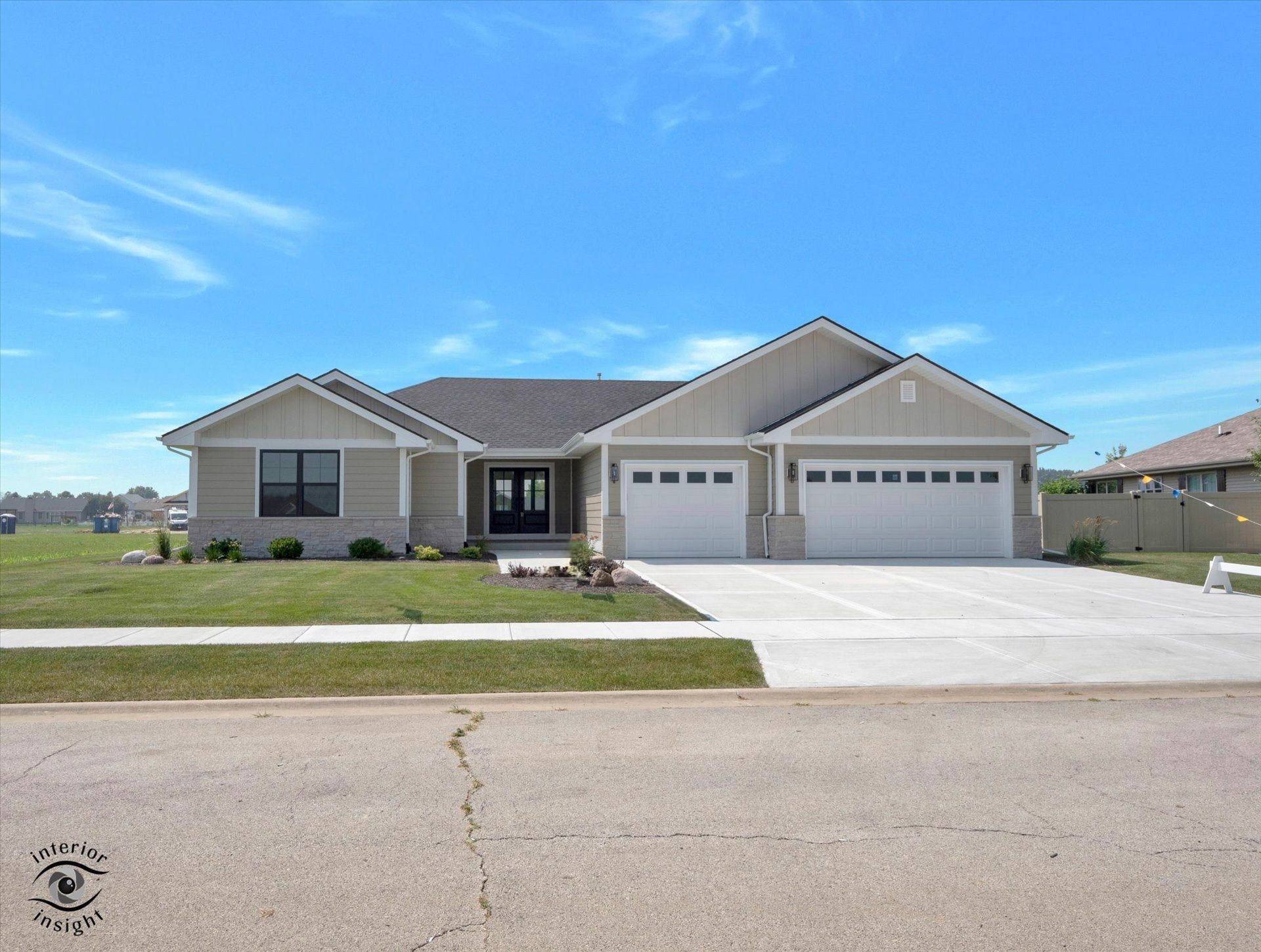 A large red and white house with two garage doors and a concrete driveway.