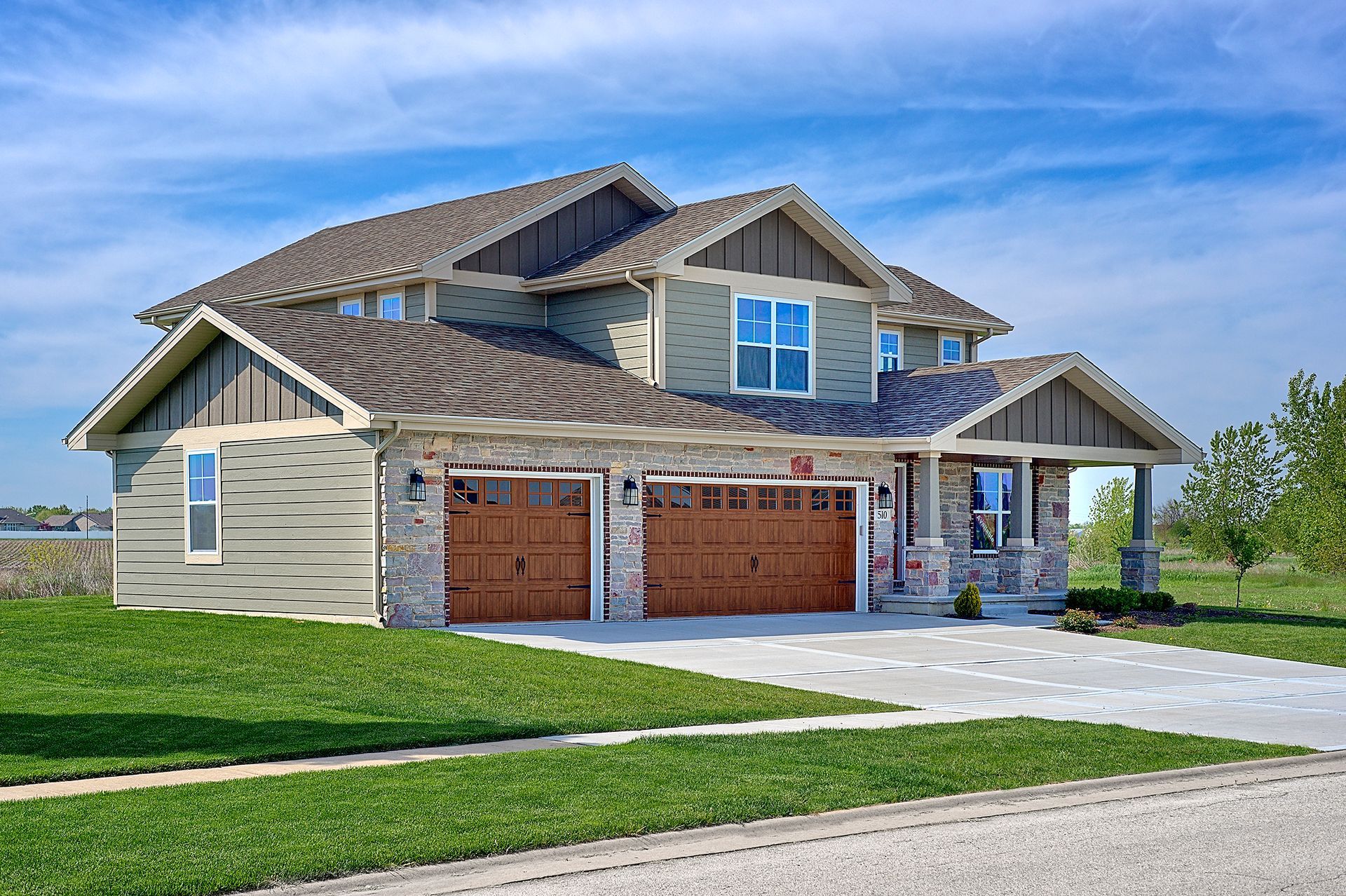A brick house with a green siding and a white garage door