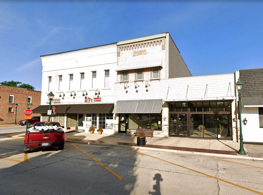 A red truck is parked in front of a white building.
