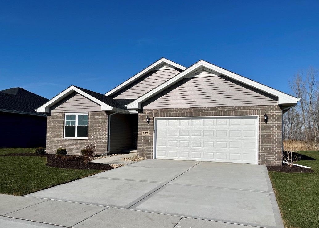 A brick house with a white garage door and a driveway.