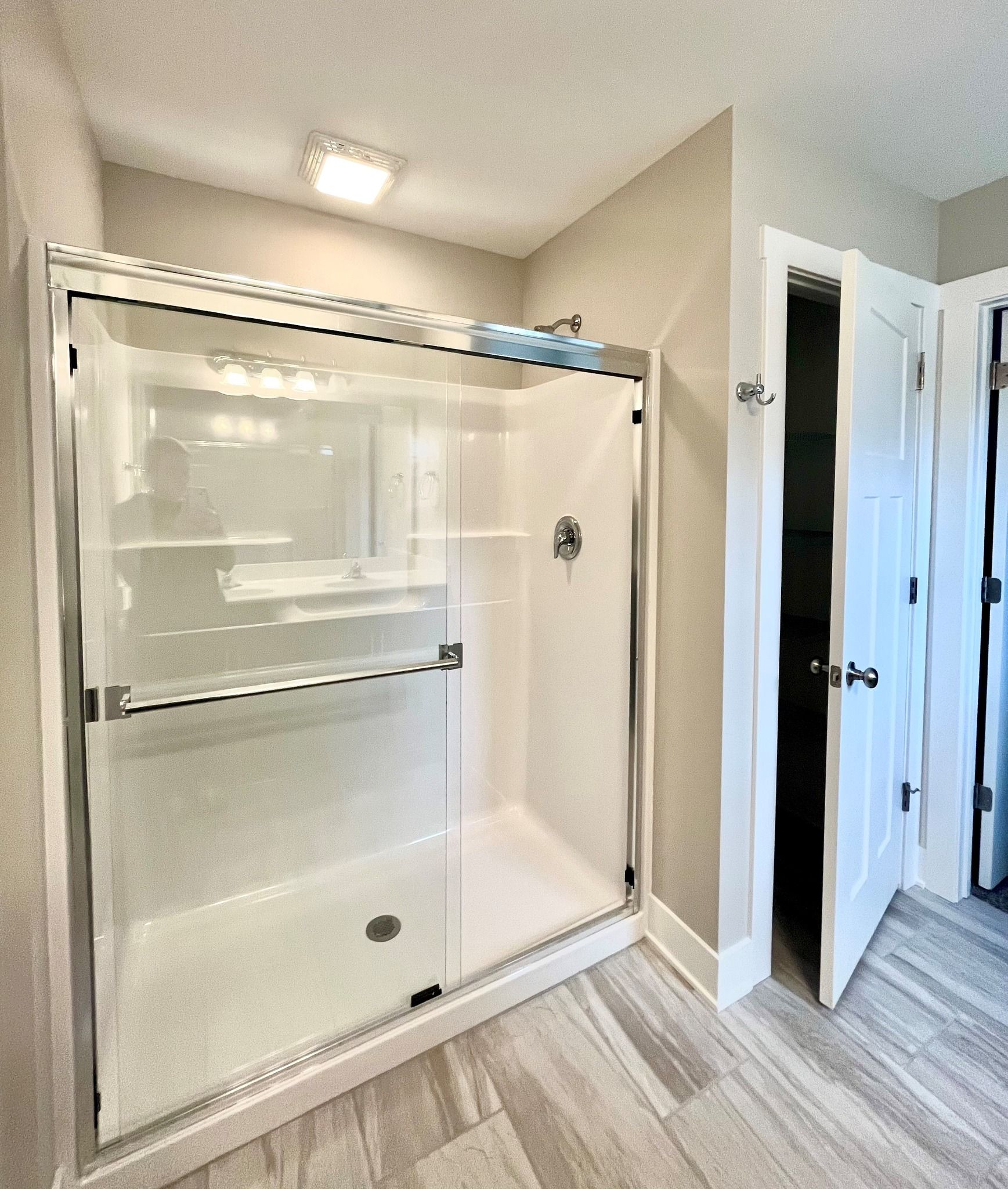 A bathroom with a walk in shower and a closet.