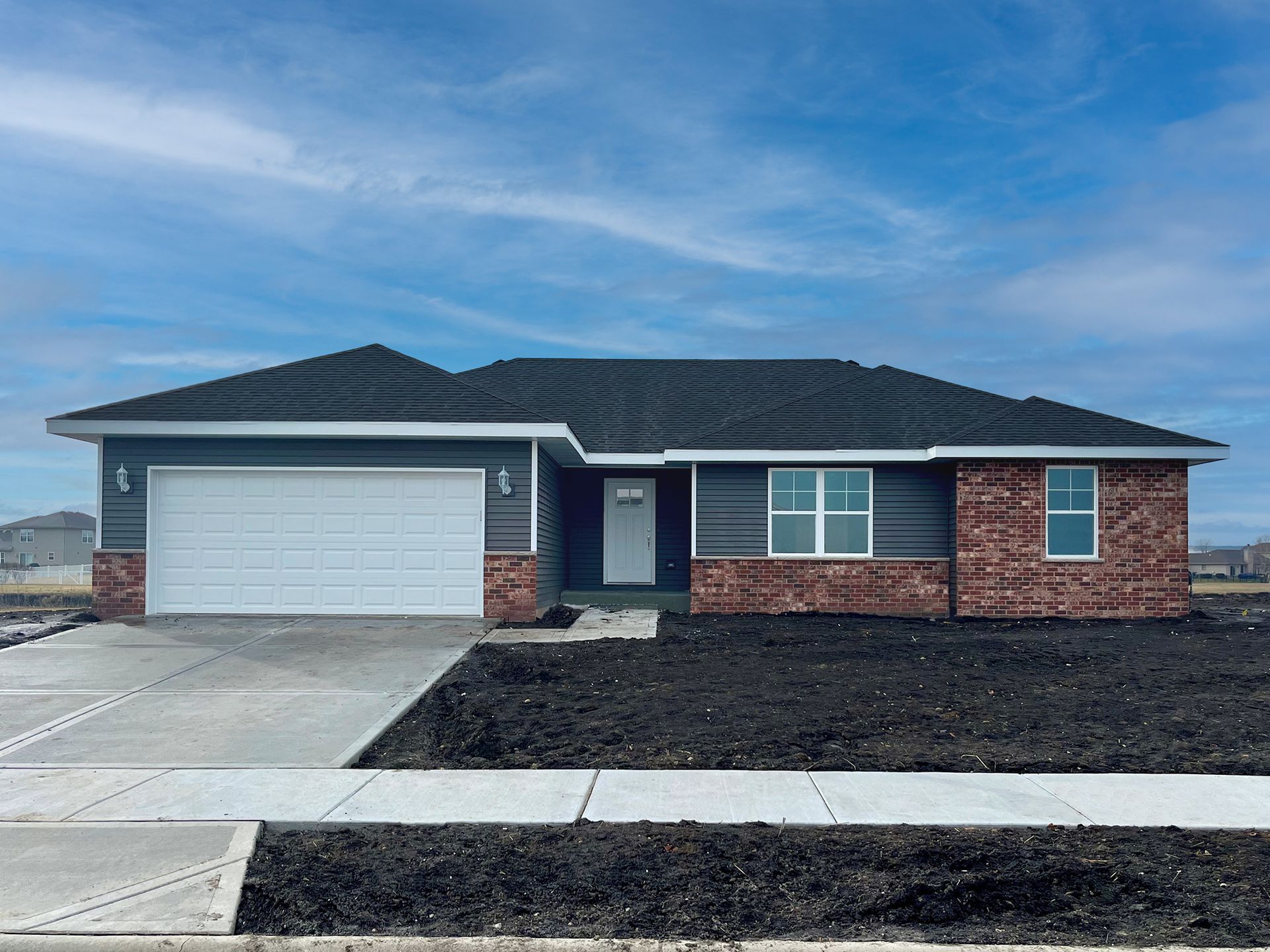 A house with a black roof and a white garage door is for sale.
