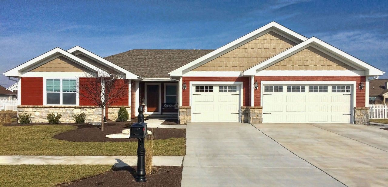 A large red and white house with two garage doors and a concrete driveway.
