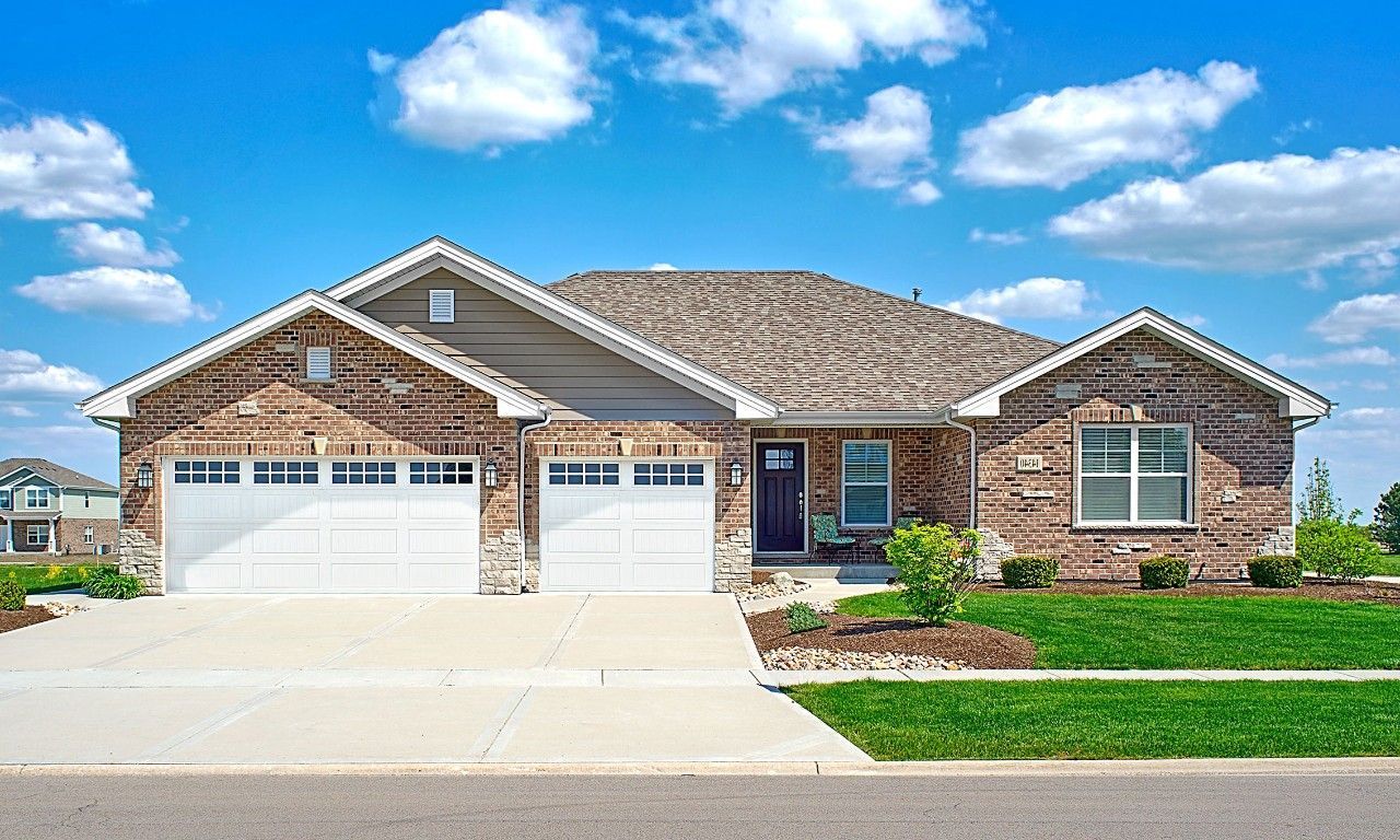 A brick house with a white garage door and a blue sky in the background.