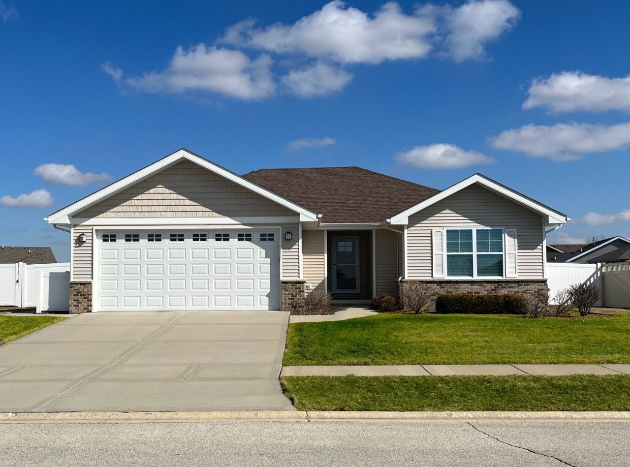 A house with a white garage door and a blue sky in the background