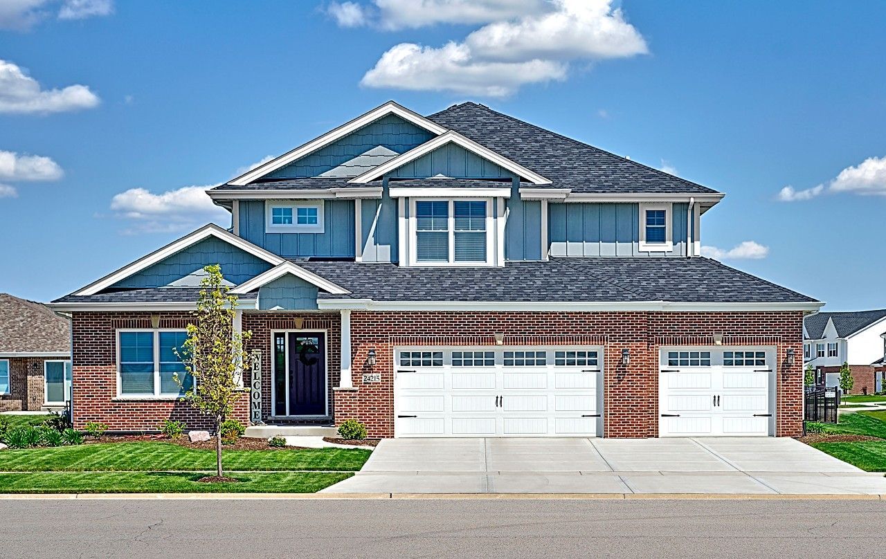 A large house with a blue roof and white garage doors.