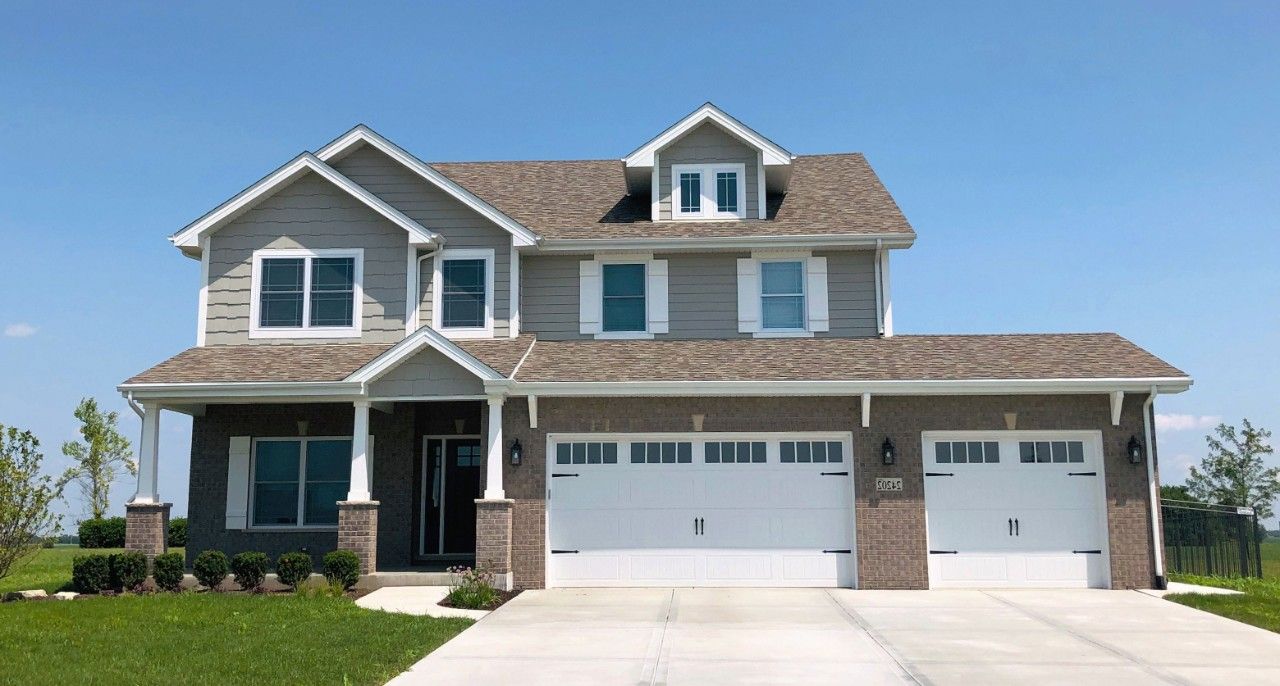 A large house with two garage doors and a driveway.